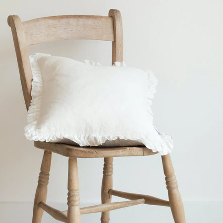 Pure white linen feather filled cushions with cottage-core style frill around the edge.