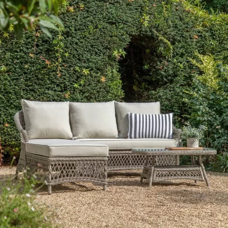 Durable all-weather rattan, beautifully hand-woven open and close weave detailing soft stone hue and built upon a sturdy aluminium frame, it’s as practical as it is pretty, with showerproof cushions for those unpredictable days. Set on a gravel drive with a mature shrub behind