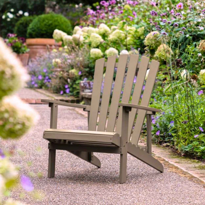 Cottage Style Grey Adirondack chair on a gravel path with garden flowers in the background