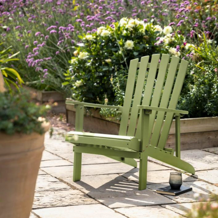 Cottage Style Green Adirondack chair on a Slabbed path with garden flowers in the background